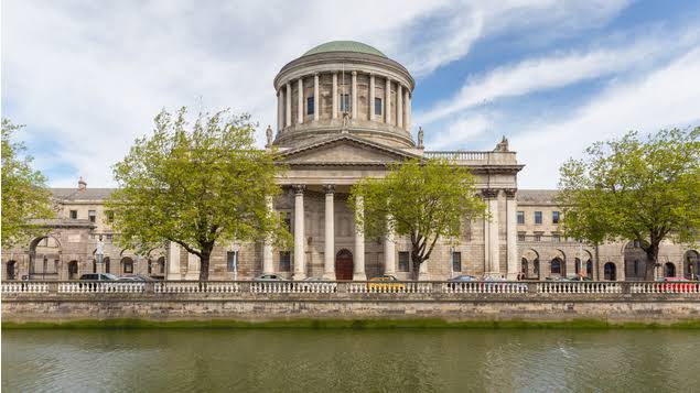 Ireland court of appeal - SAVE TOGLIATTIAZOT (TOAZ) Neoclassical riverside building with a large dome and columns, framed by trees along a stone promenade beside a calm river.